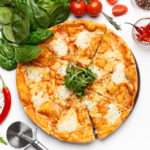 Italian Mozzarella Pizza On White Table, Top View Italian Mozzarella Pizza And Basil Leaves Nearby On White Table, Top View, Crop