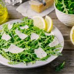 Rocket salad with Parmesan cheese, lemon, olive oil and seasonings Rocket salad with Parmesan cheese, lemon, olive oil and seasonings on wooden background